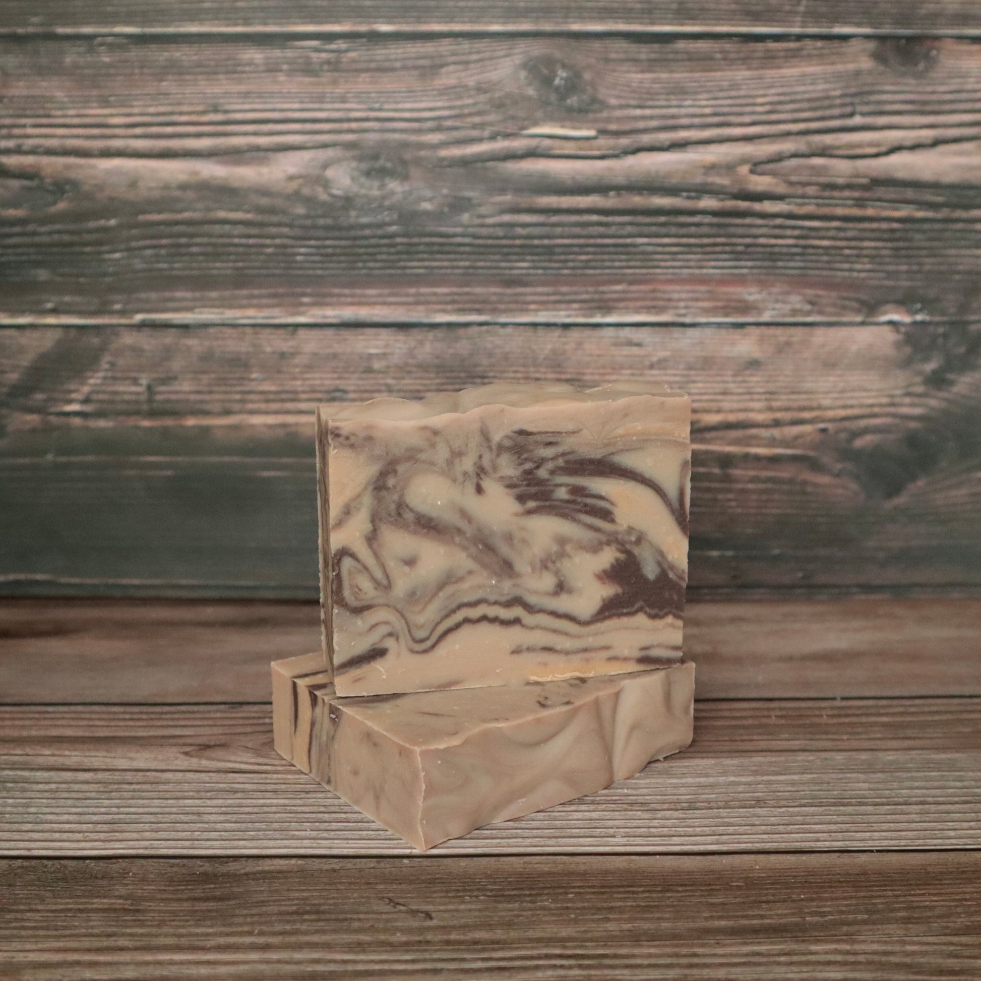 Two bars of soap with wood-colored swirls to resemble wood. The background also looks like wood.